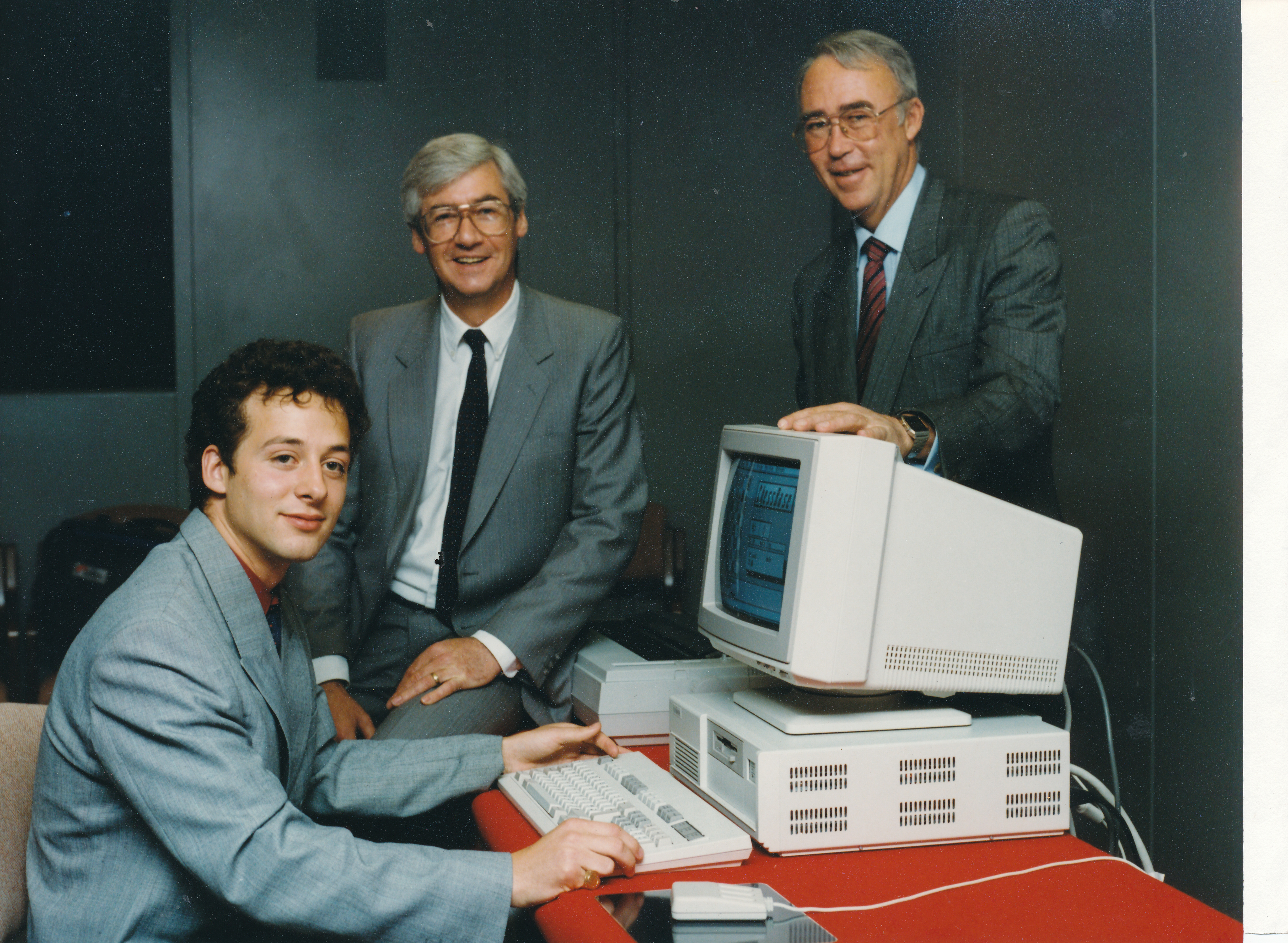 A powerful Unisys personal computer being present to Bolton-born GM David Norwood by Alva Rodger (centre), general manager of Unisys banking district ad Dr Brian Bailey, managing director of Infolink, a credit referencing agency.