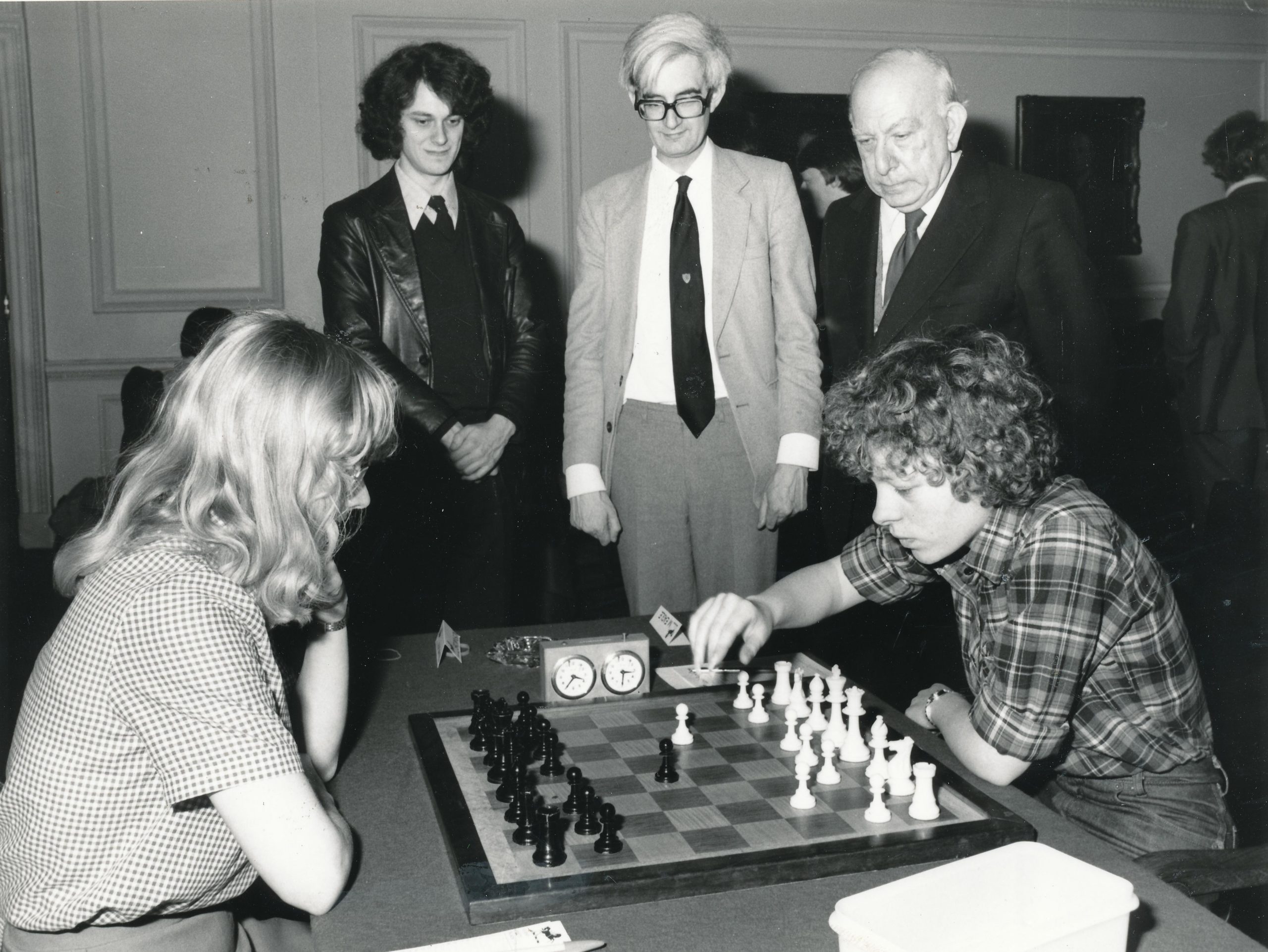 Linda Brownson (Newnham & Basildon), left, playing Maria Eagle (Pembroke & Formby) being observed by John Nunn, Adrian Hollis and Harry Golombek posing for the obligatory "staring at the board" picture for the 1981 Varsity Match sponsored by Lloyds Bank. 