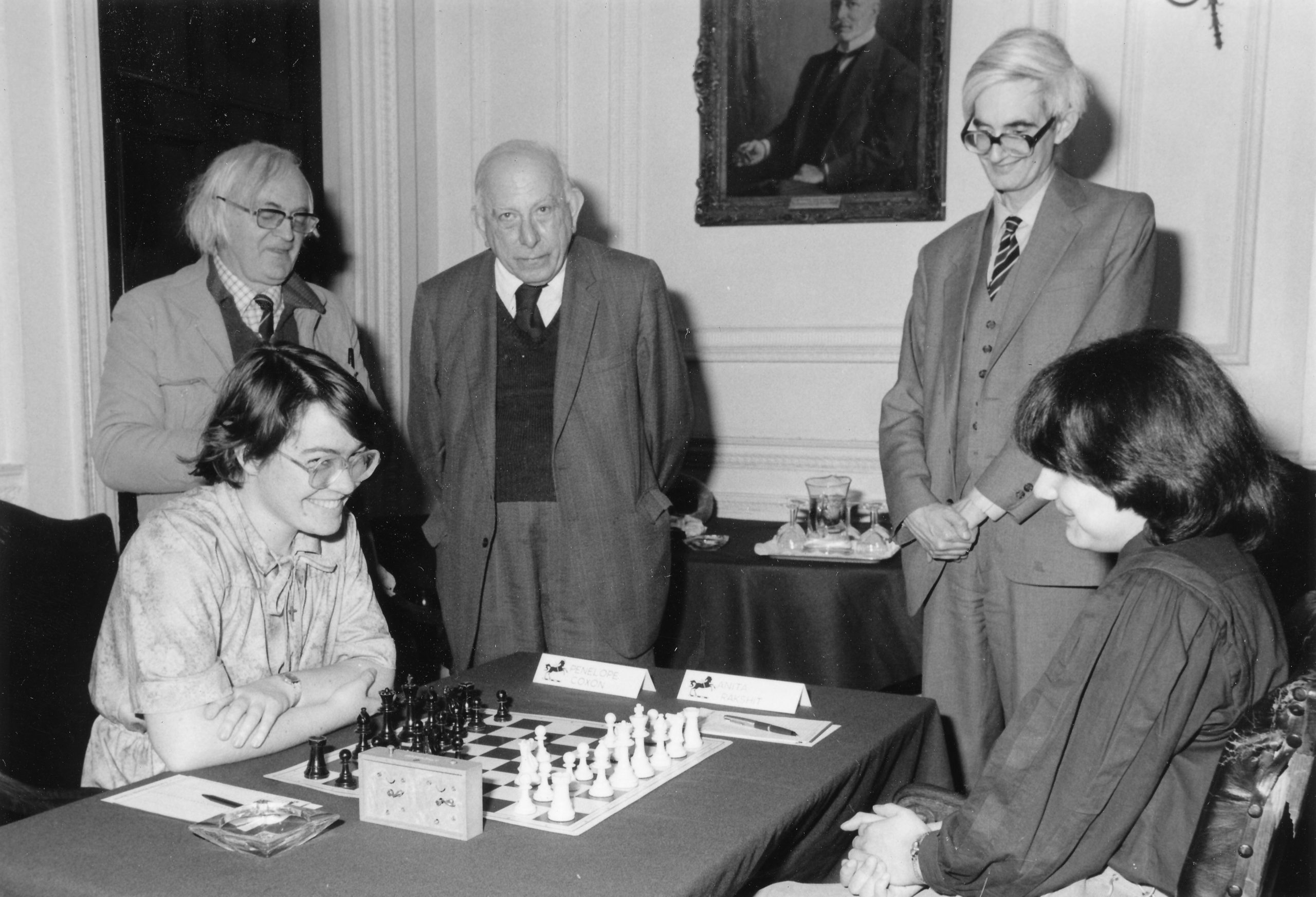 Bob Wade, Harry Golombek and Adrian Hollis observe Penny Coxon (Newnam) and Anita Rakshit (St. Hilda's) during the 1983 Varsity match sponsored by Lloyds Bank